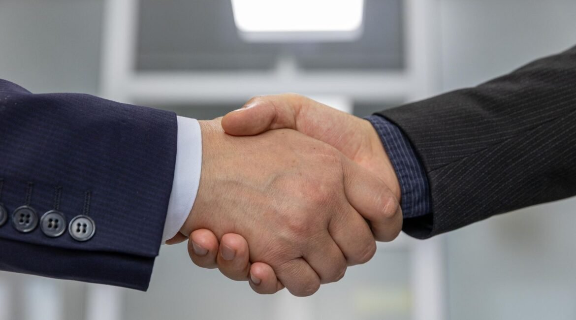 Aperto de mãos entre dois executivos, simbolizando confiança e credibilidade da reputação empresarial